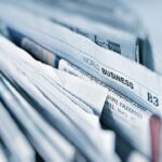 Nahaufnahme eines Stapels Tageszeitungen mit der Überschrift ‚World Business‘ – Symbolbild für Wandel und Umbruch in der Medienbranche