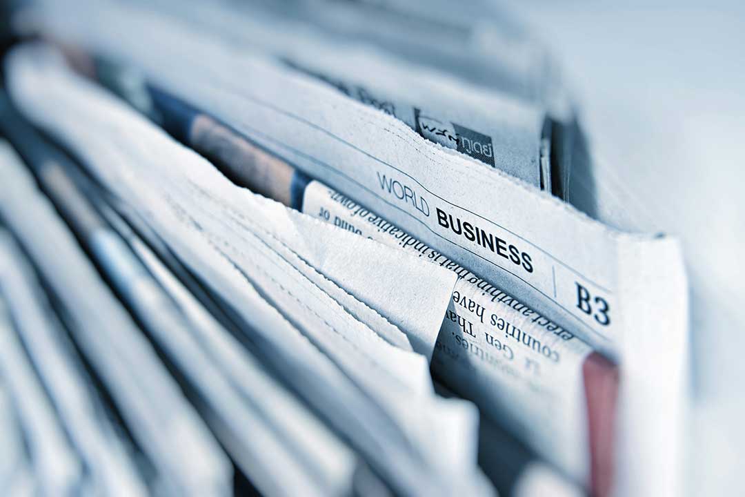 medienbranche-zukunft-beratung Nahaufnahme eines Stapels Tageszeitungen mit der Überschrift ‚World Business‘ – Symbolbild für Wandel und Umbruch in der Medienbranche