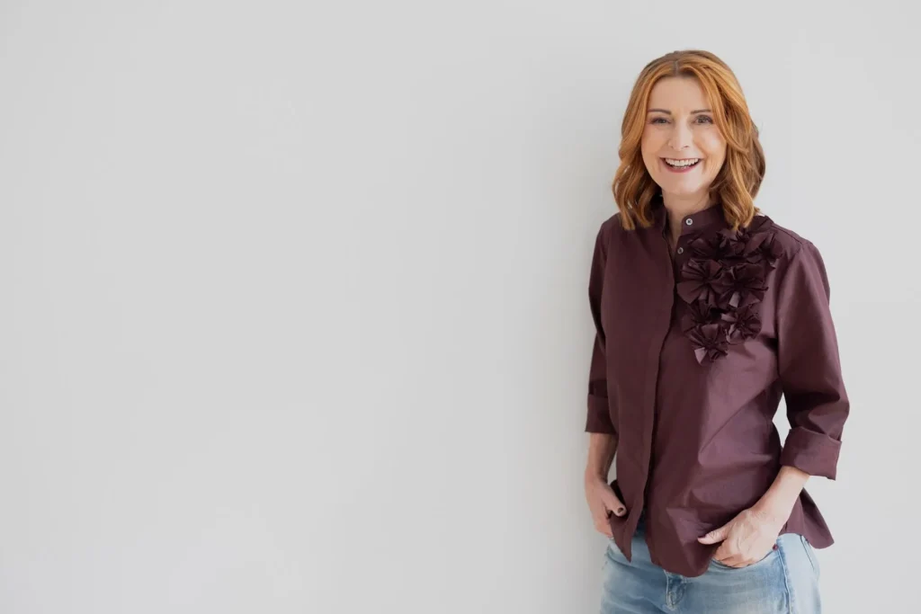 Karin Hübner, Karrierecoach für Medienprofis, lächelt in die Kamera, Hände in den Hosentaschen